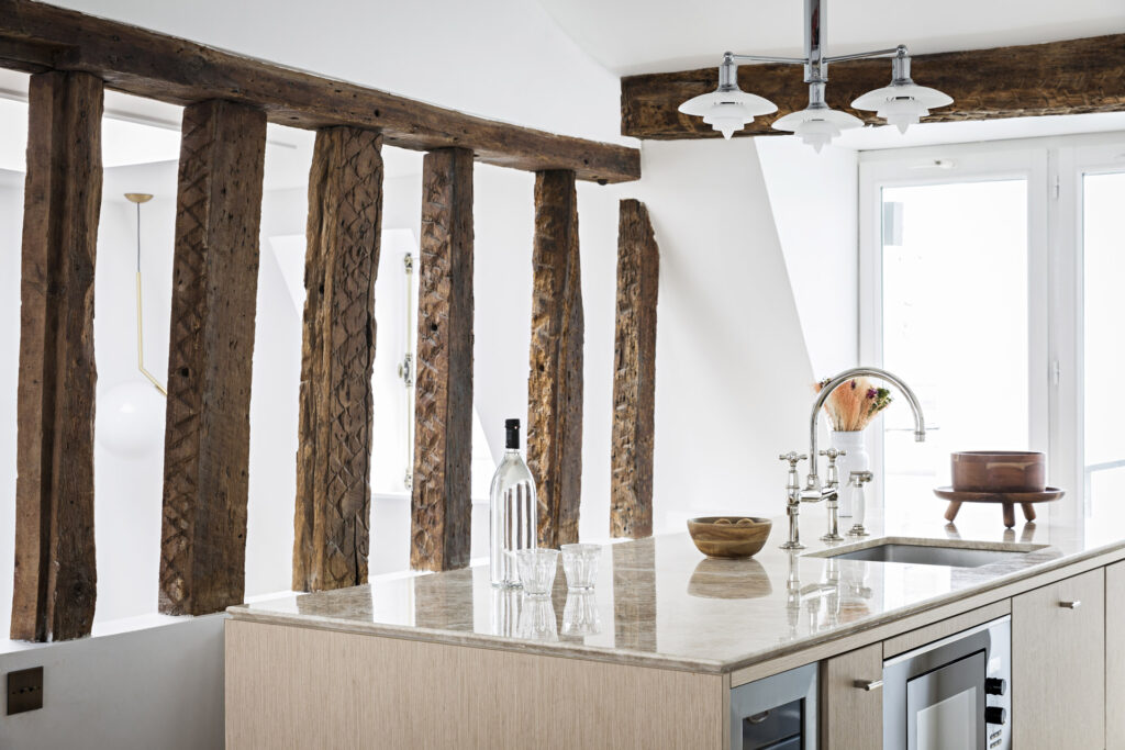 Cuisine ouverte du triplex Thérèse à Paris, intégrée dans un espace à poutres visibles et décorée avec une élégance discrète par Olivia Massimi.